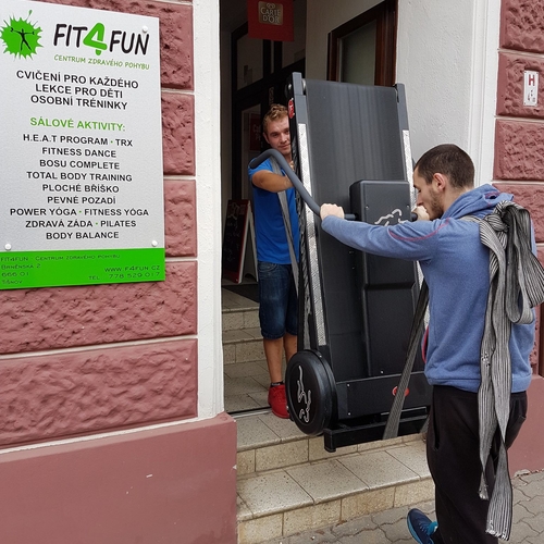 Stěhováci z Brna vynášející běžecký pás z posilovny do nákladního auta